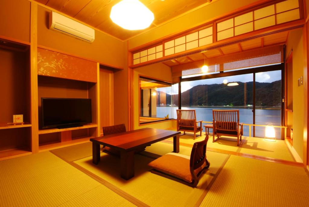 un salon avec une table, des chaises et une télévision dans l'établissement Ginka, à Toyooka