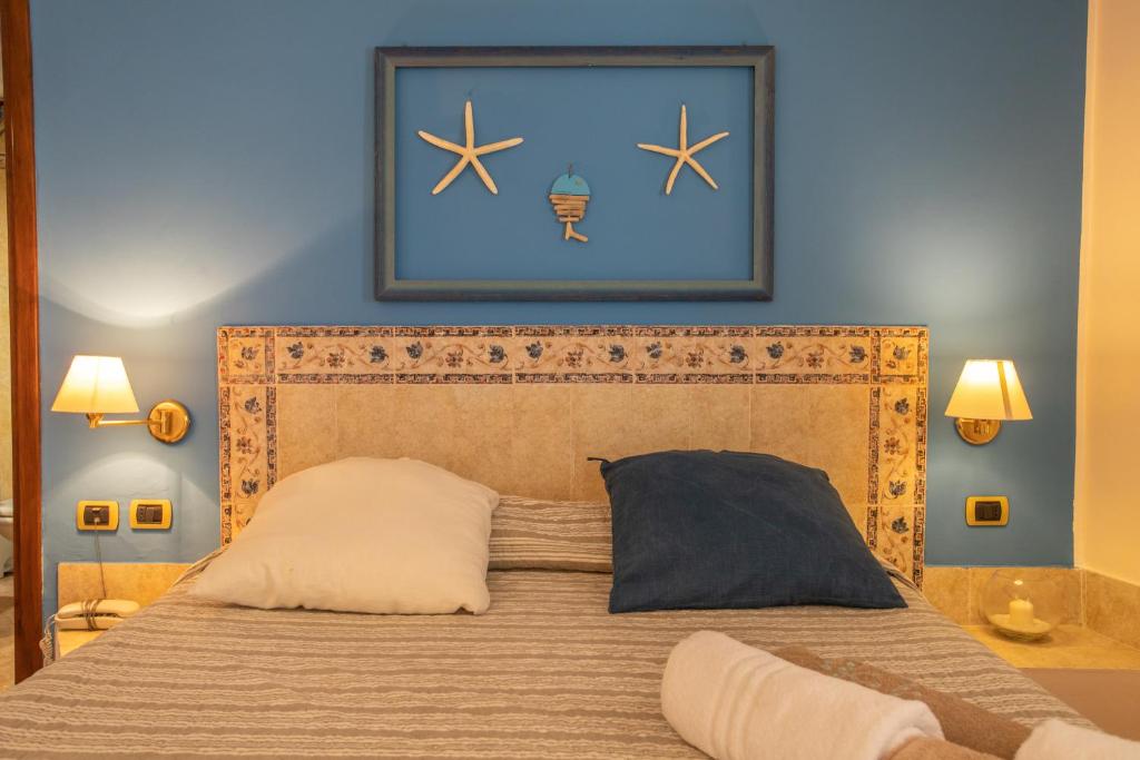 une chambre avec un lit avec un tableau sur le mur dans l'établissement Relais Isole del Sud, à Lampedusa