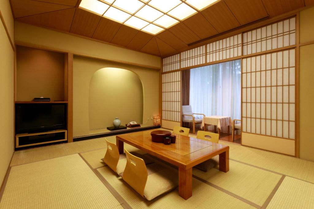 un salon avec une table en bois et une télévision dans l'établissement Izumigo Kiyosato Kogen Hotel, à Hokuto