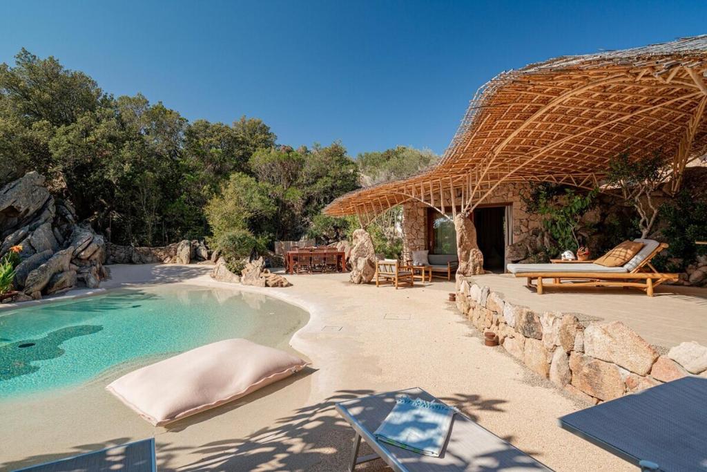 un complexe avec une piscine et un toit de chaume dans l'établissement Villa Ninfea - sea view and relax, à Porto Taverna