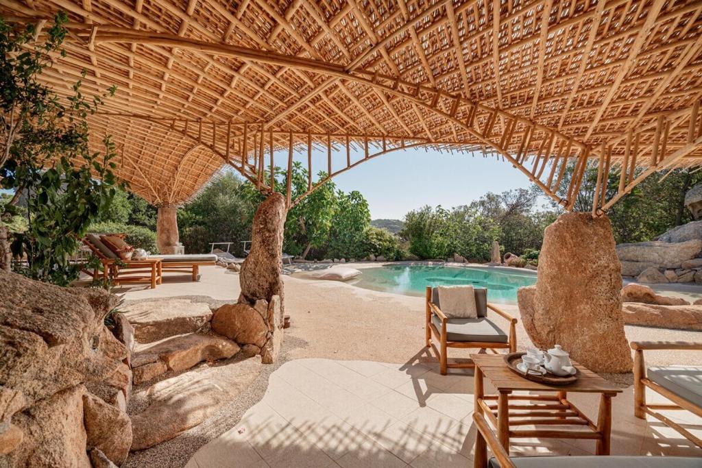 un complexe avec une piscine et un toit de paille dans l'établissement Villa Ninfea - sea view and relax, à Porto Taverna