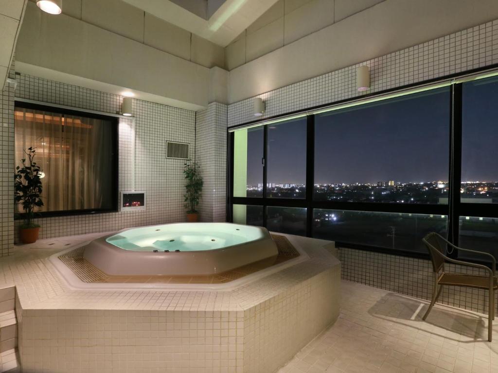 La salle de bains est pourvue d'une baignoire et offre une vue sur la ville. dans l'établissement G HOTEL 一宮 -Hotel & Resorts-, à Inazawa