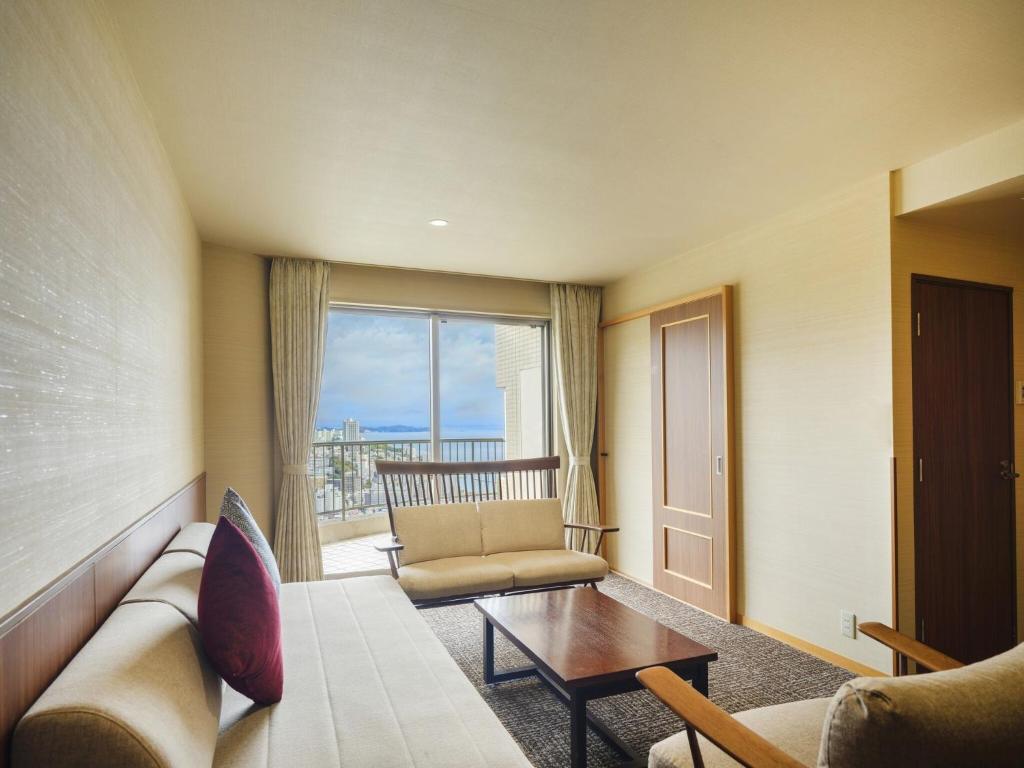 un salon avec un canapé, une table et une fenêtre dans l'établissement KAMENOI HOTEL Atami, à Atami