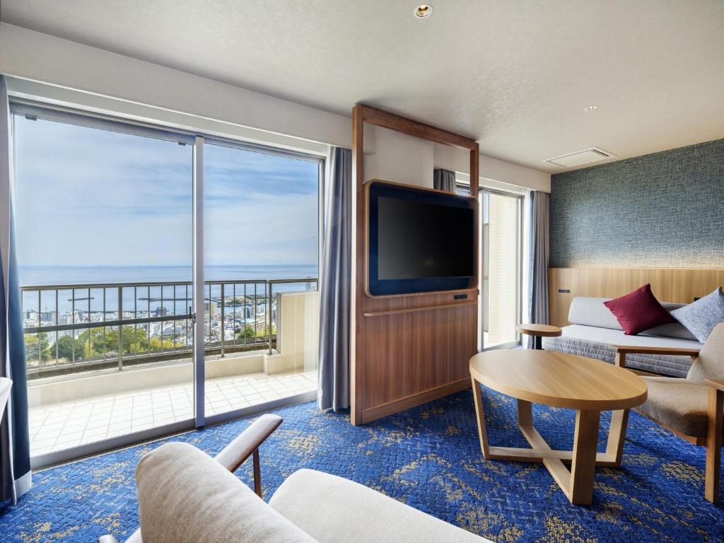 une chambre d'hôtel avec une grande fenêtre et un salon dans l'établissement KAMENOI HOTEL Atami, à Atami