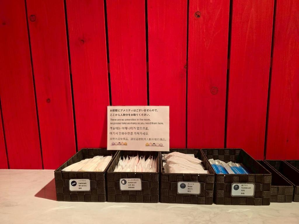 une exposition de brosses à dents dans des boîtes devant un mur rouge dans l'établissement Auberge Ninguruforet, à Biei
