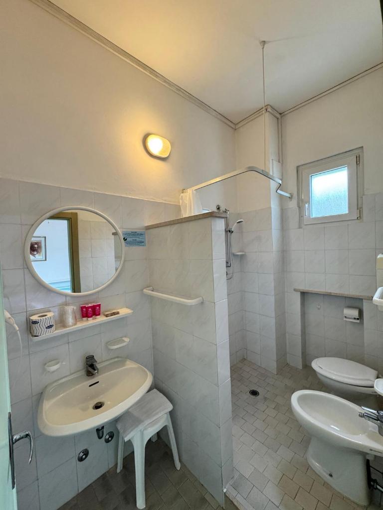 une salle de bain blanche avec un lavabo et un miroir dans l'établissement Hotel Urania Nuova Gestione, à Rimini
