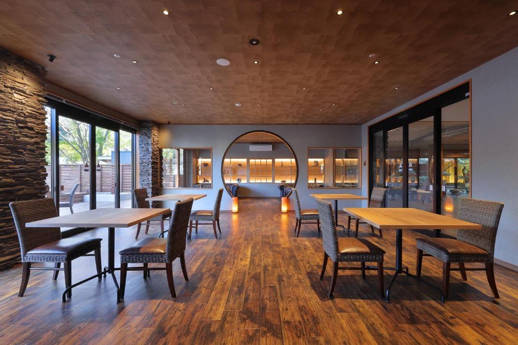 un restaurant avec des tables et des chaises en bois et des fenêtres dans l'établissement Marukyu Ryokan, à Izu
