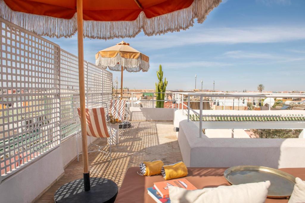 une terrasse avec un parasol, un canapé et une table dans l'établissement Riad Brummell Medina, à Marrakech