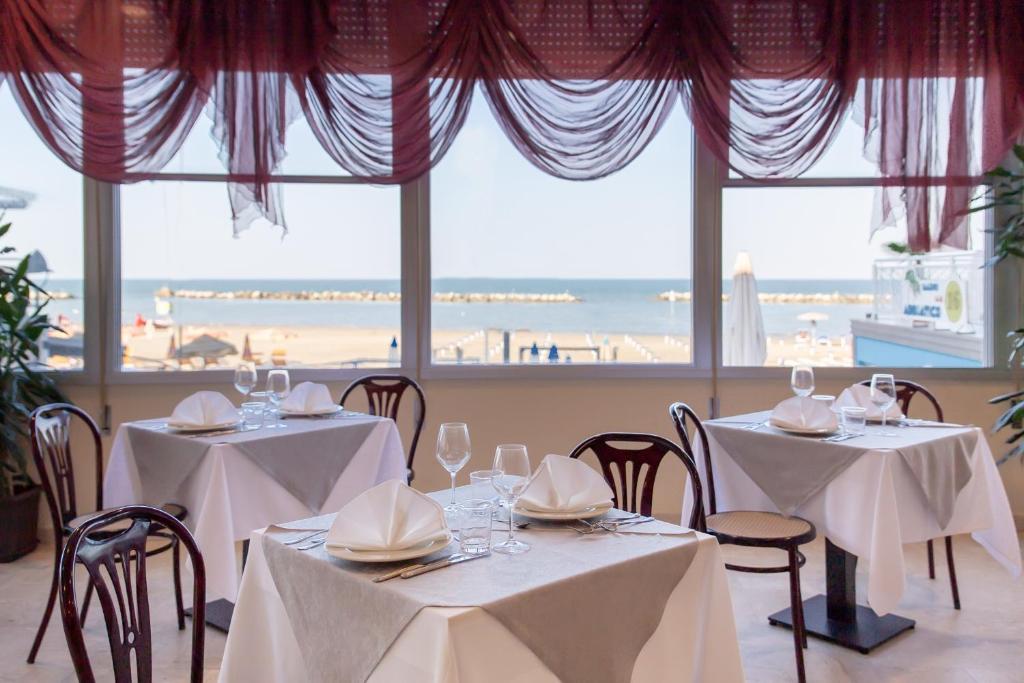 - une salle à manger avec deux tables et une vue sur la plage dans l'établissement Hotel Bamby e Delfino, à Gatteo a Mare