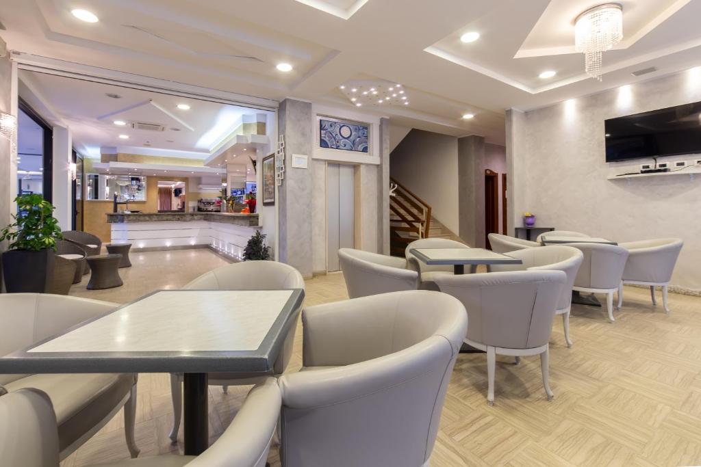 - une salle d'attente avec des tables et des chaises blanches dans l'établissement Hotel Bamby e Delfino, à Gatteo a Mare