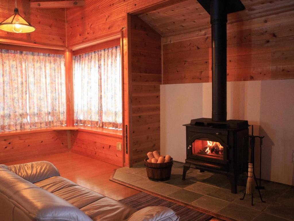 un salon avec une cheminée et un canapé dans l'établissement Izumigo AMBIENT Azumino Cottage, à Azumino