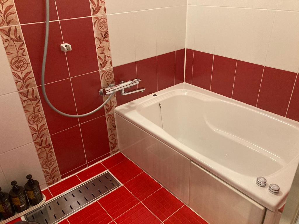 La salle de bains est pourvue d'une baignoire blanche et de carreaux rouges. dans l'établissement ホテルバレンタインb館 ビジネスステイ, à Tottori 11 autres photos