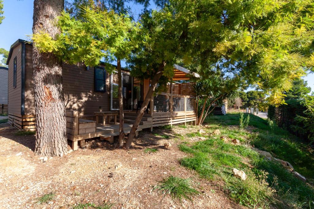 une cabane en rondins avec une véranda à côté d'un arbre dans l'établissement Camping Lou Soulei 218, à Carry-le-Rouet