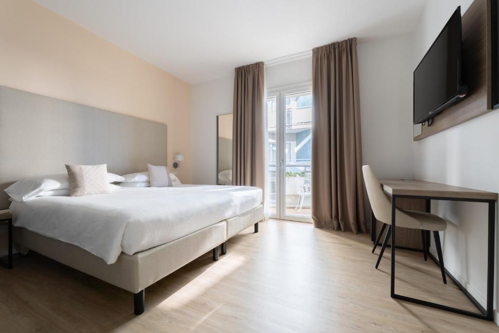 une chambre avec un lit, un bureau et une télévision dans l'établissement Hotel Excelsior, à Lido di Jesolo