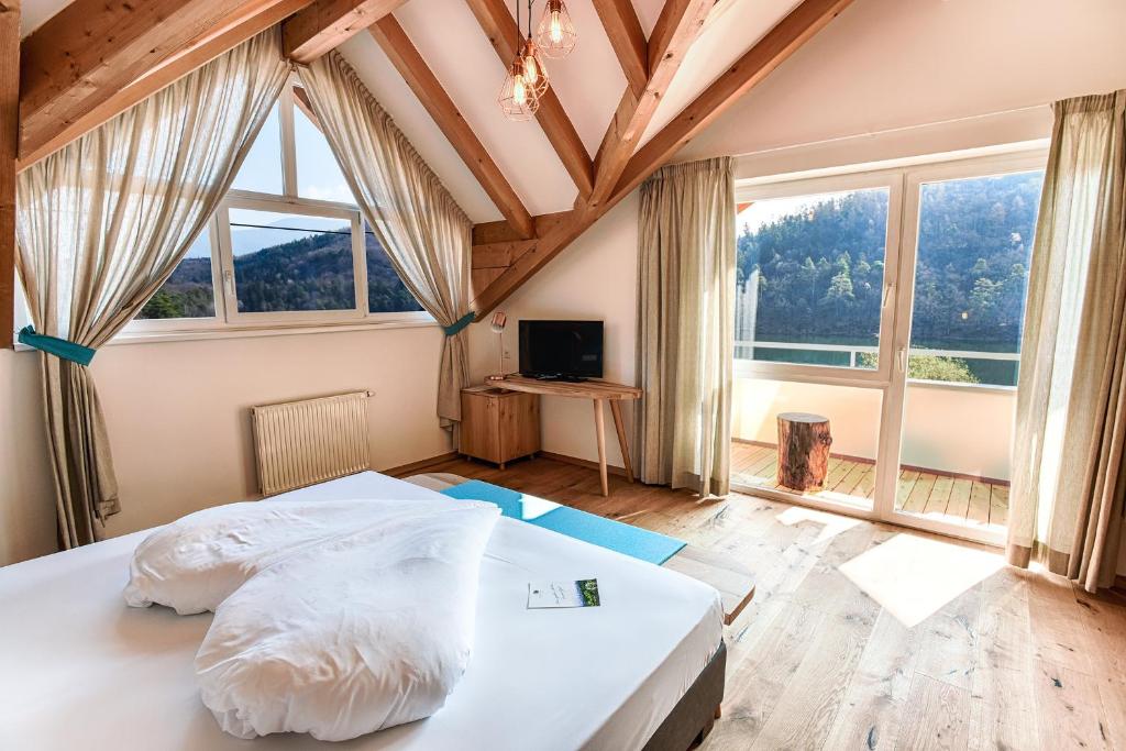 - une chambre avec un grand lit dans une pièce dotée de fenêtres dans l'établissement Seehotel Sparer, à Appiano sulla Strada del Vino