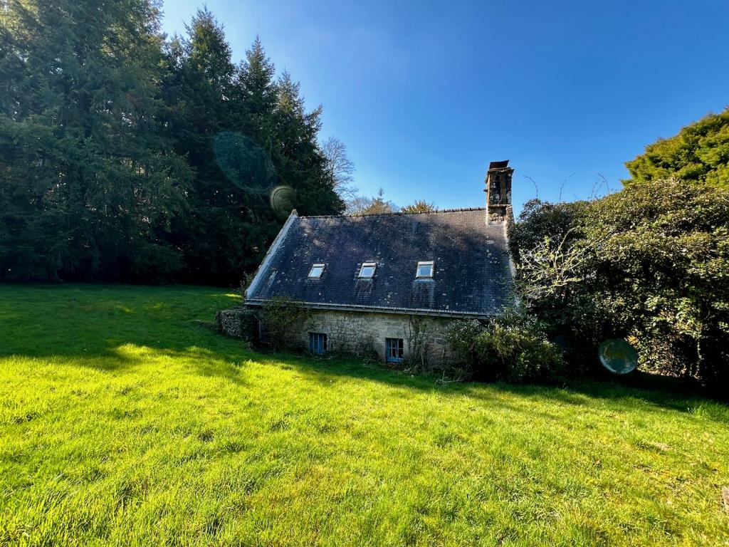 une ancienne maison en pierre dans un champ recouvert d'herbe dans l'établissement Gîtes du Gohic - Le Cidre, à Quistinic