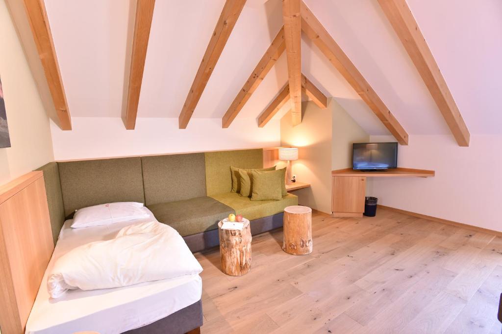 une chambre mansardée avec un lit et une télévision dans l'établissement Seehotel Sparer, à Appiano sulla Strada del Vino