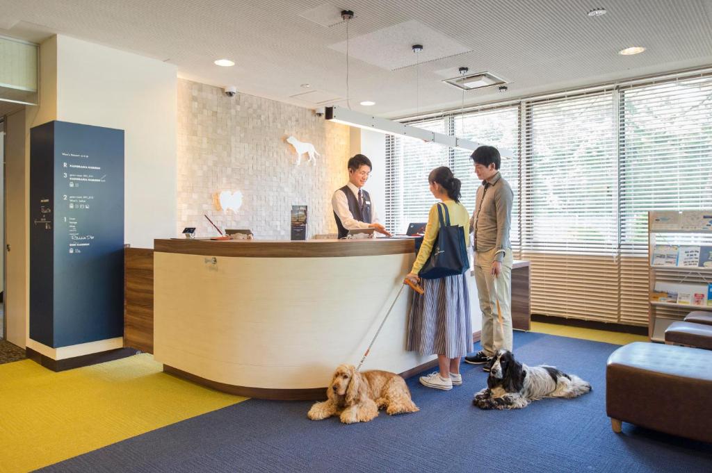 un groupe de personnes debout à un comptoir avec deux chiens dans l'établissement Wan's Resort Yamanakako, à Yamanakako