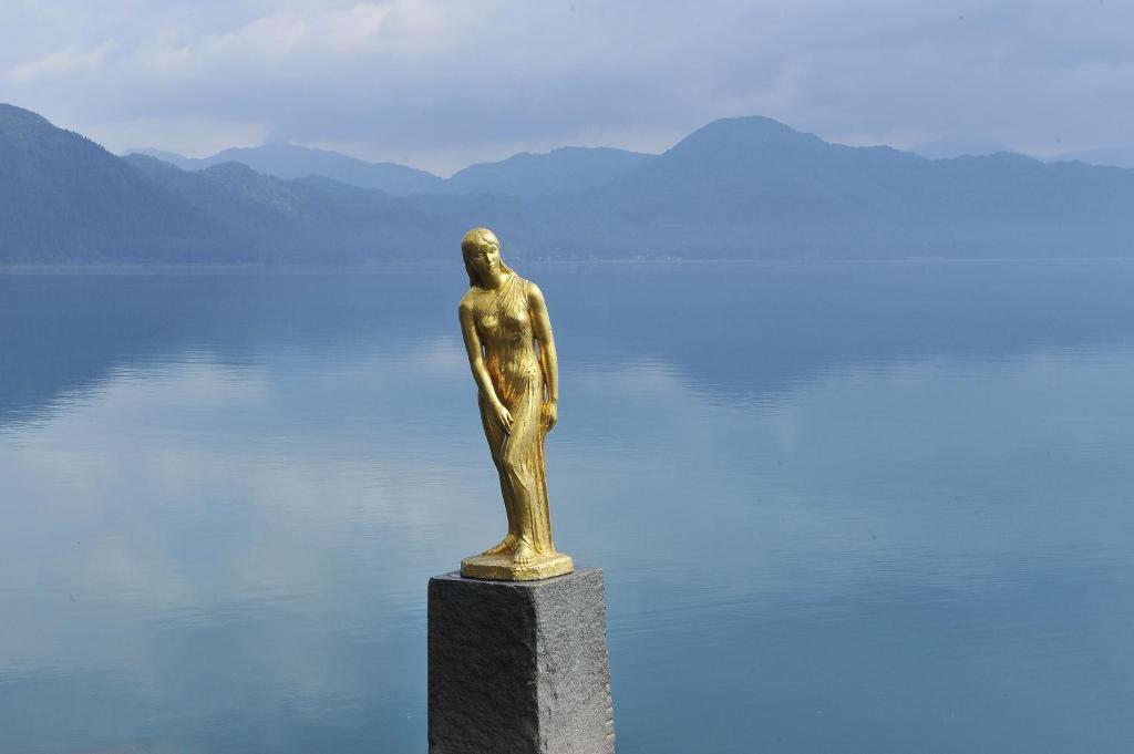 une statue de bronze assise au sommet d'un plan d'eau dans l'établissement KAMENOI HOTEL Tazawako, à Senboku