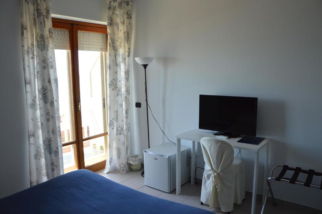 une chambre avec un lit et un bureau avec une télévision dans l'établissement Hotel Piccolo Paradiso, à Bordighera