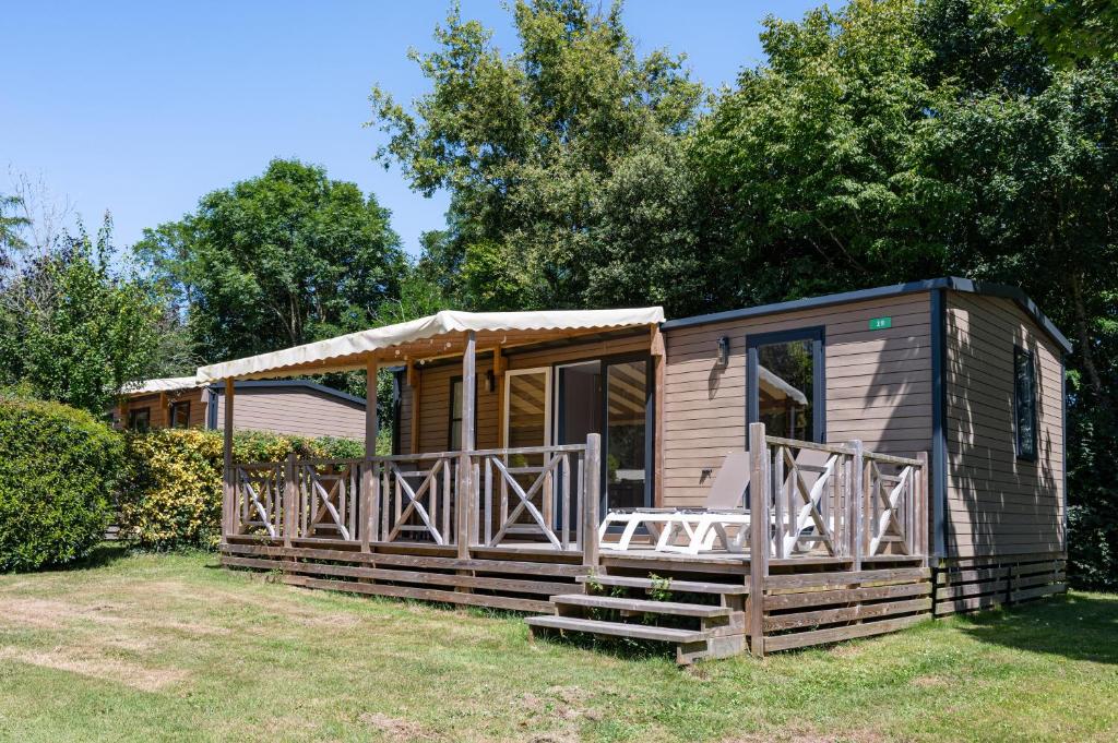 une cabane en bois avec une terrasse couverte sur la pelouse dans l'établissement Camping RCN La Ferme du Latois, à Coëx 29 autres photos