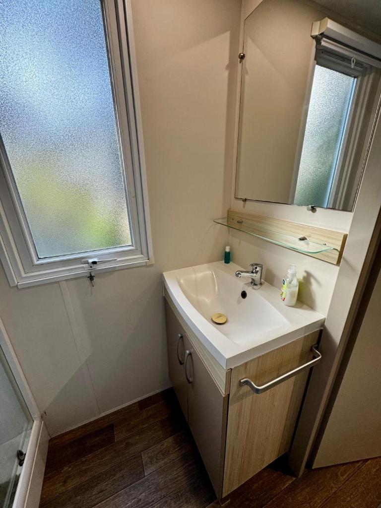 une salle de bain avec un lavabo, un miroir et une fenêtre dans l'établissement Au cœur des Pins, à Camiers 6 autres photos