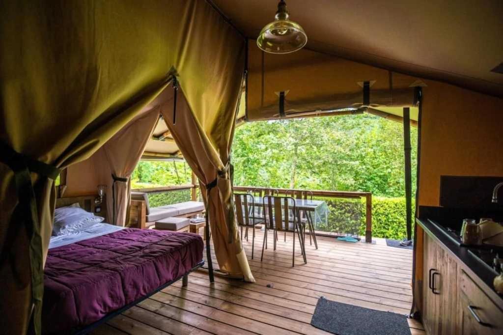 Cette tente comprend une chambre dotée d'une terrasse avec une table et des chaises. dans l'établissement Camping 4 étoiles - Piscine - ccbabhc, à Aramits