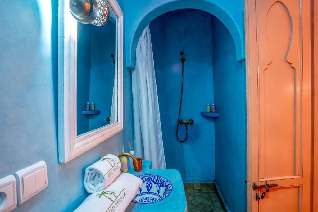 une salle de bain bleue avec un lavabo et un miroir dans l'établissement Riad dar ennakhla, à Marrakech