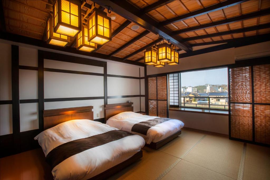 une chambre avec deux lits et une grande fenêtre dans l'établissement Yuyaruru Saisai, à Kanazawa