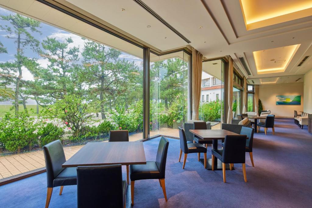 un restaurant avec des tables et des chaises et de grandes fenêtres dans l'établissement Shiraraso Grand Hotel, à Shirahama