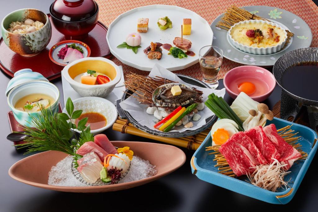une table avec des assiettes et des bols de nourriture dans l'établissement Shiraraso Grand Hotel, à Shirahama
