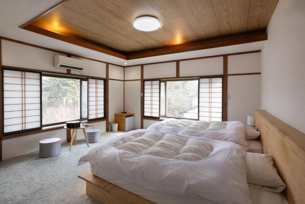 Cette chambre comprend un grand lit et des fenêtres. dans l'établissement Hotakajo, à Azumino
