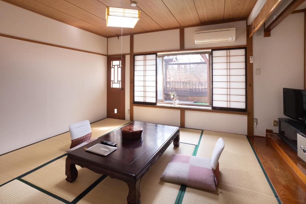 un salon avec une table, des chaises et une télévision dans l'établissement Hotakajo, à Azumino