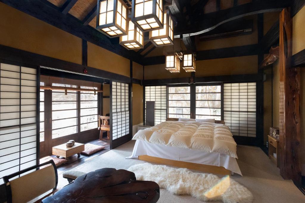 - une chambre avec un grand lit dans une pièce dotée de fenêtres dans l'établissement Hotakajo, à Azumino