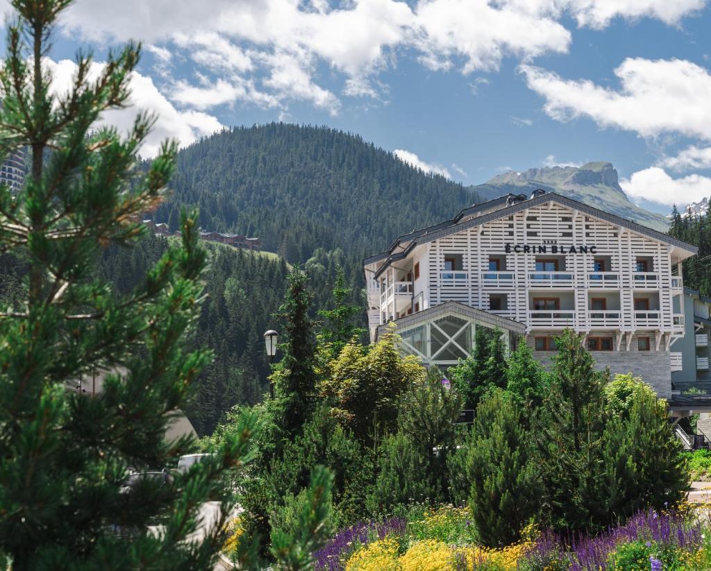 un bâtiment dans les montagnes avec des fleurs devant dans l'établissement Ecrin Blanc Resort Courchevel - Aquapark, à Courchevel 37 autres photos