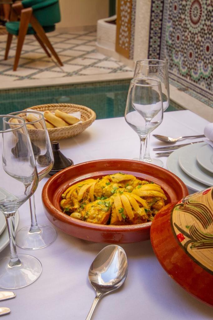 - une table avec un bol de pâtes et des verres à vin dans l'établissement Riad Jalina, à Marrakech