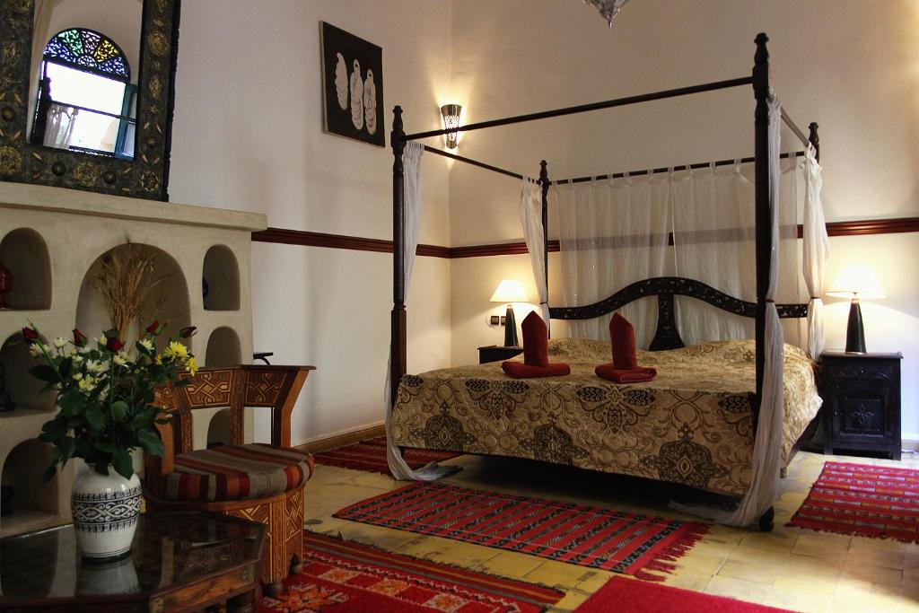 - une chambre avec un lit à baldaquin et des oreillers rouges dans l'établissement Riad Jomana, à Marrakech