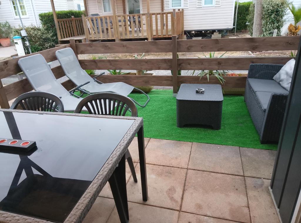 d'une terrasse avec des chaises, une table et de l'herbe verte. dans l'établissement Europcamping, à Fréjus