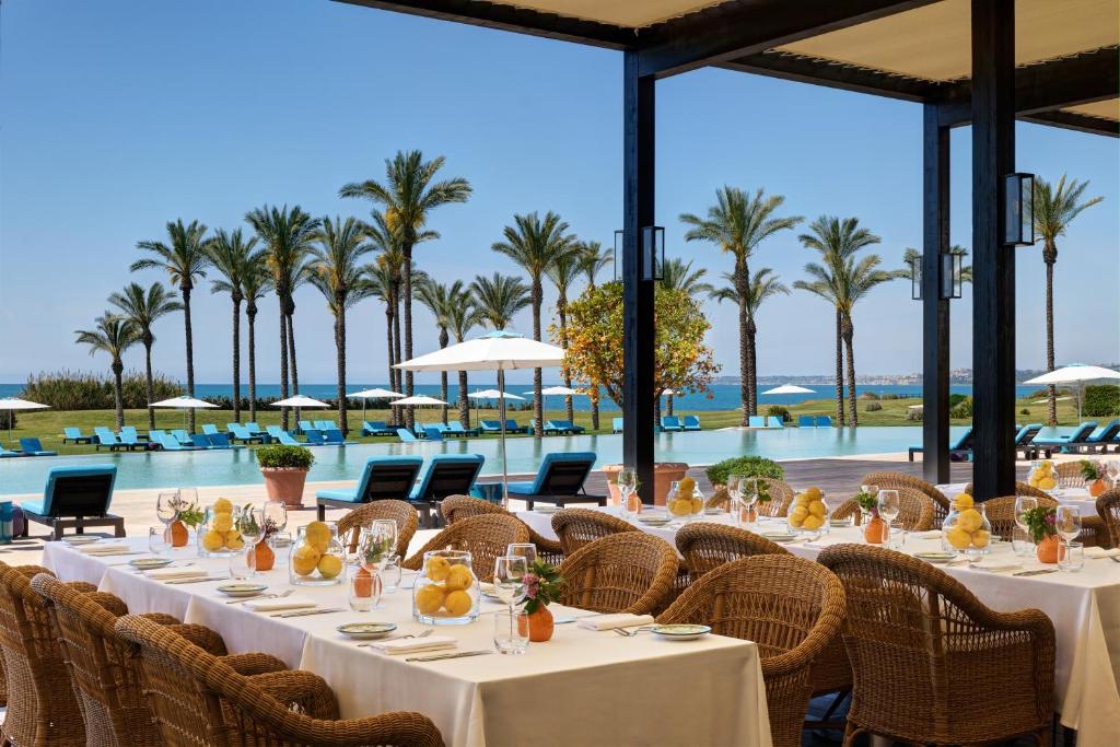 une salle à manger avec tables et chaises et une piscine dans l'établissement Verdura Resort, à Ribera