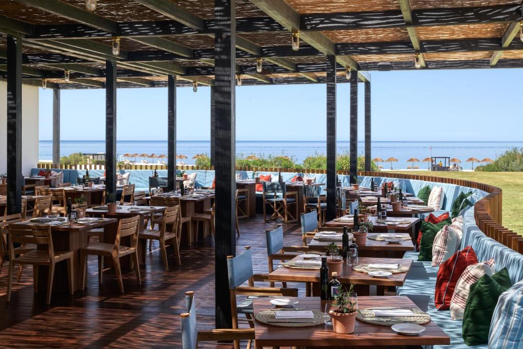 un restaurant avec des tables et des chaises et l'océan en arrière-plan dans l'établissement Verdura Resort, à Ribera