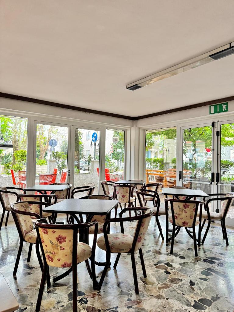 une salle à manger avec tables, chaises et fenêtres dans l'établissement Hotel Urania Nuova Gestione, à Rimini