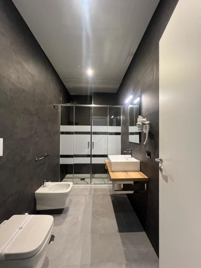 La salle de bains est pourvue de 2 lavabos, de toilettes et d'une douche. dans l'établissement Hotel TEA - Praia a Mare, à Praia a Mare