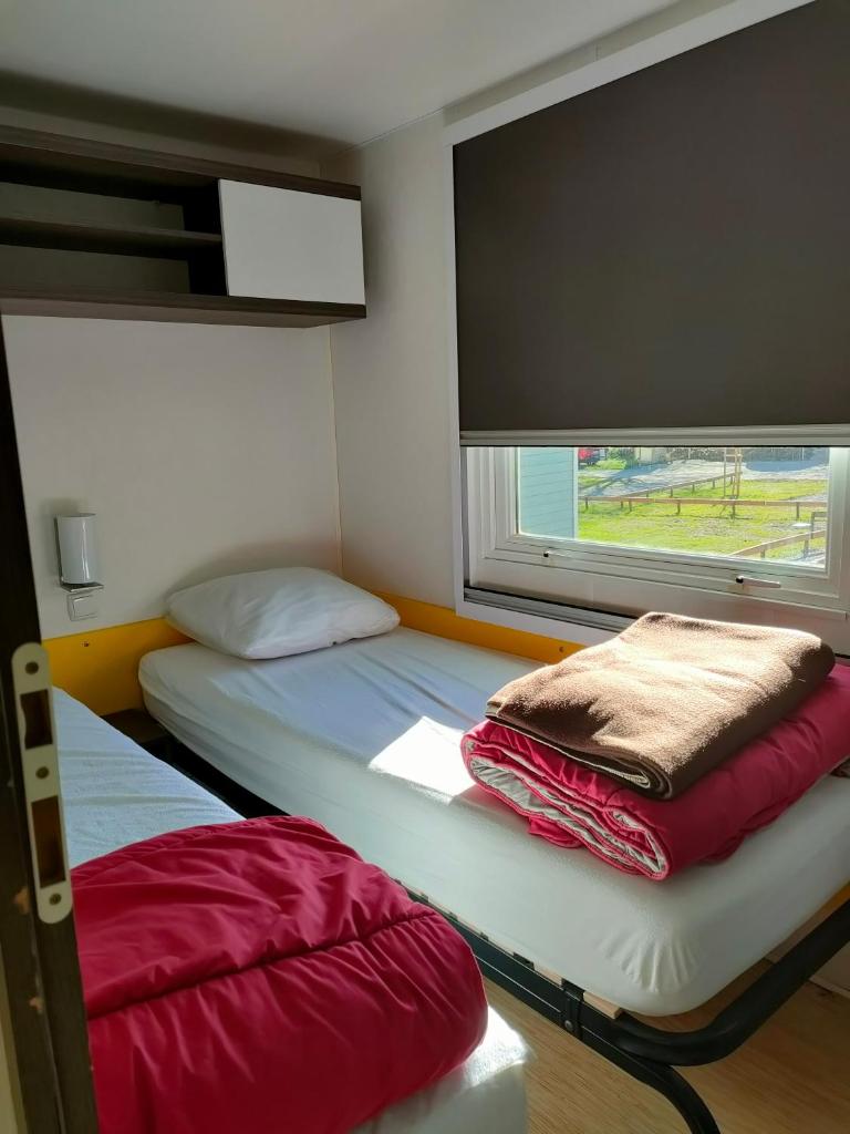 une petite chambre avec deux lits et une fenêtre dans l'établissement Camping du Moulin de Thoard, à Thoard 37 autres photos