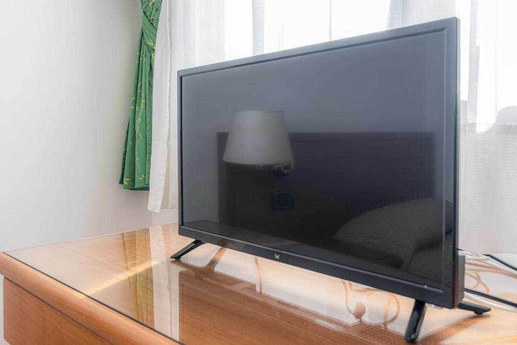 Une grande télévision à écran plat est installée au-dessus d'une table. dans l'établissement Hotel A' CAPANNA, à Diamante