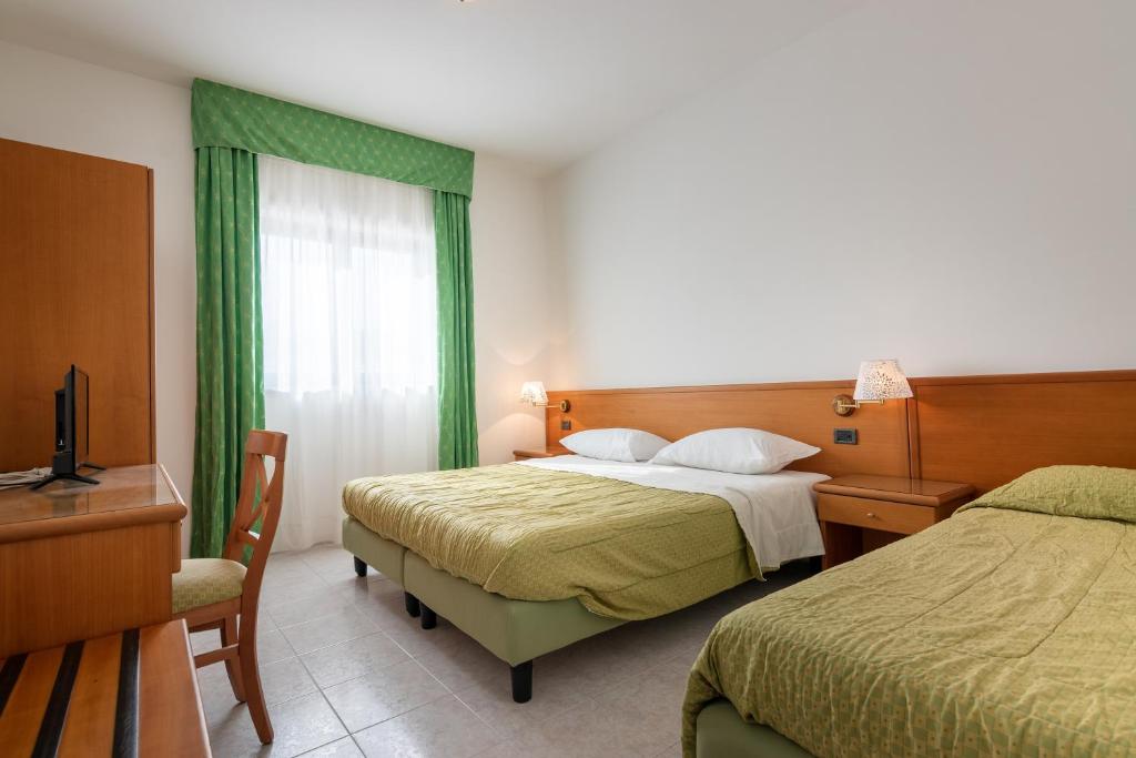 une chambre avec deux lits, un bureau et une télévision dans l'établissement Hotel A' CAPANNA, à Diamante 7 autres photos