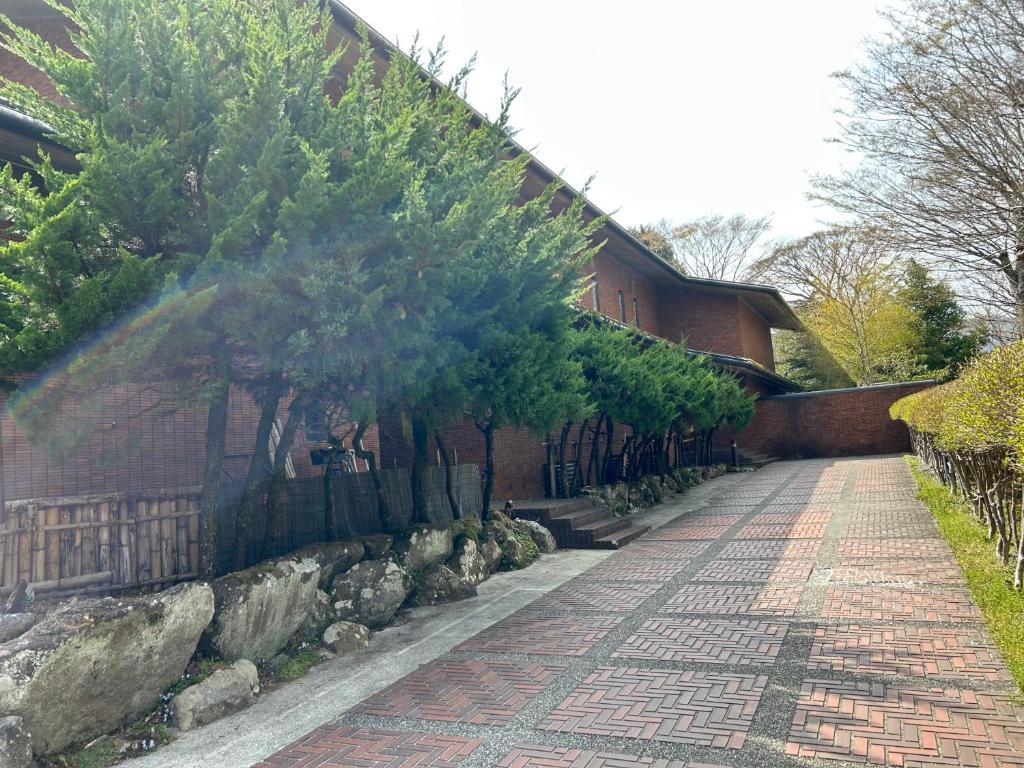 un trottoir en briques à côté d'un bâtiment avec des arbres dans l'établissement Kozuka Hisanoha, à Hakone