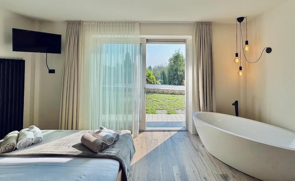 La salle de bains est pourvue d'une grande baignoire, d'un lit et d'une baignoire. dans l'établissement Villa Essenza, à Barcuzzi