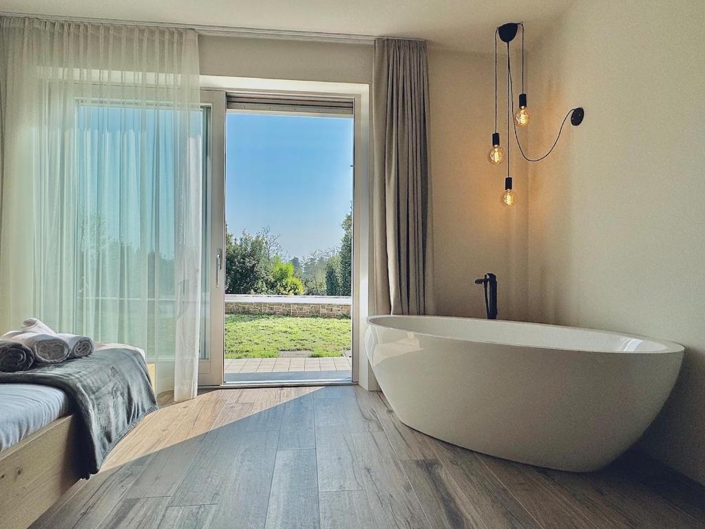 La salle de bains est pourvue d'une grande baignoire blanche devant une fenêtre. dans l'établissement Villa Essenza, à Barcuzzi