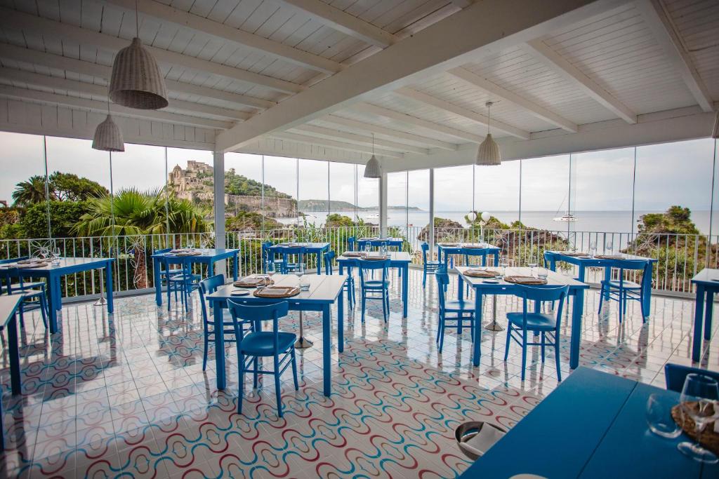 un restaurant avec des tables et des chaises bleues et l'océan dans l'établissement Strand Hotel Delfini, à Ischia