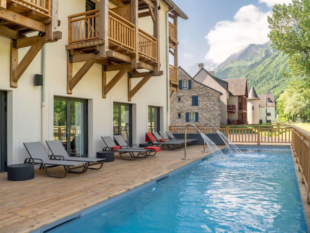 une maison dotée d'une piscine avec des chaises et une terrasse dans l'établissement Mercure Peyragudes Loudenvielle Pyrénées, à Loudenvielle